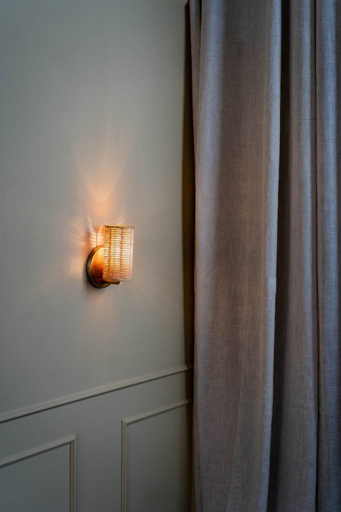 Handcrafted Costa Wall Lamp Mini Rattan Brass with natural rattan cylindrical shade.