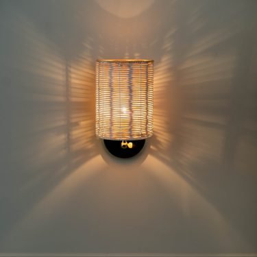 Handcrafted Costa Wall Lamp Cylindrical Rattan/Brass with a natural rattan cylindrical shade and brass accents.