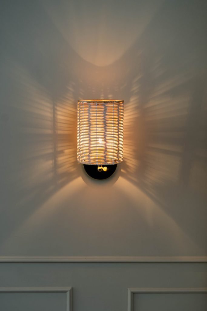 Handcrafted Costa Wall Lamp Cylindrical Rattan/Brass with a natural rattan cylindrical shade and brass accents.