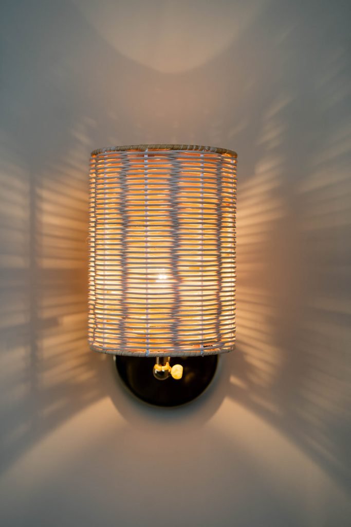 Handcrafted Costa Wall Lamp Cylindrical Rattan/Brass with a natural rattan cylindrical shade and brass accents.