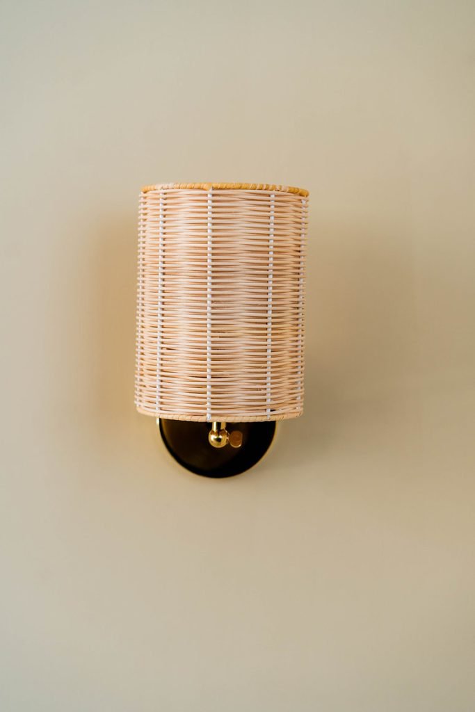 Handcrafted Costa Wall Lamp Cylindrical Rattan/Brass with a natural rattan cylindrical shade and brass accents.