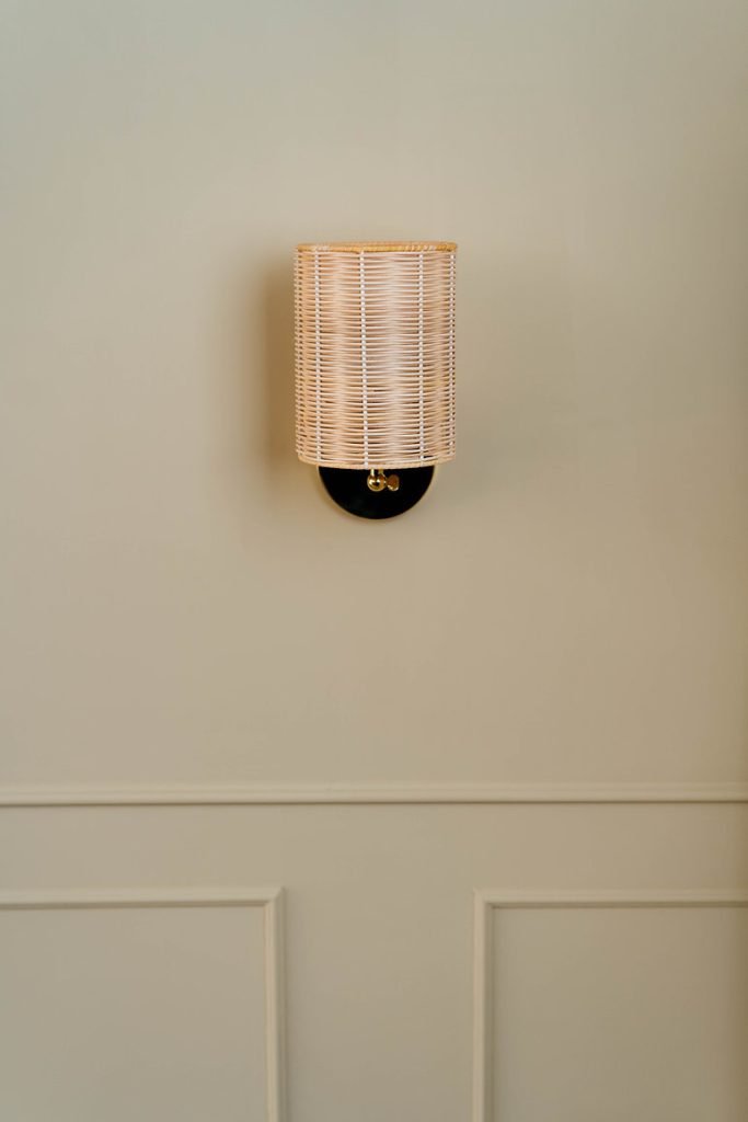 Handcrafted Costa Wall Lamp Cylindrical Rattan/Brass with a natural rattan cylindrical shade and brass accents.