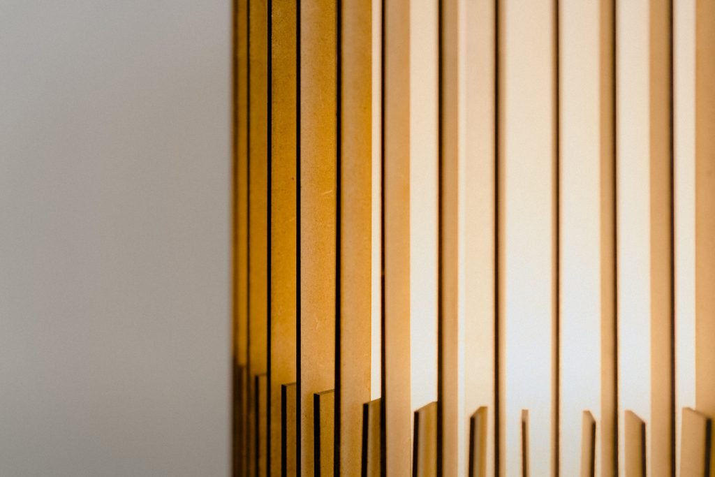 Handcrafted SUA Wall Sconce Lamp S with MDF wood slats and brass, featuring dual shades for warm light.